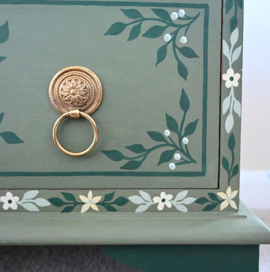 Hand-painted red wooden dresser with two drawers, featuring colorful floral folk-art motifs and decorative borders.