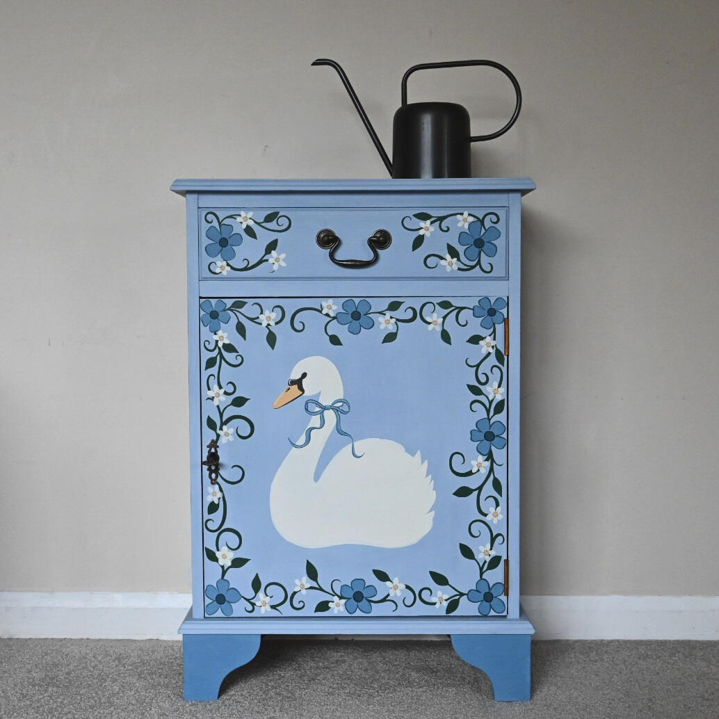 Vintage hand painted 'swan' cabinet “Hand-painted blue wooden cabinet with swan design, floral detailing, vintage style bedside table or storage cupboard, unique upcycled furniture.”