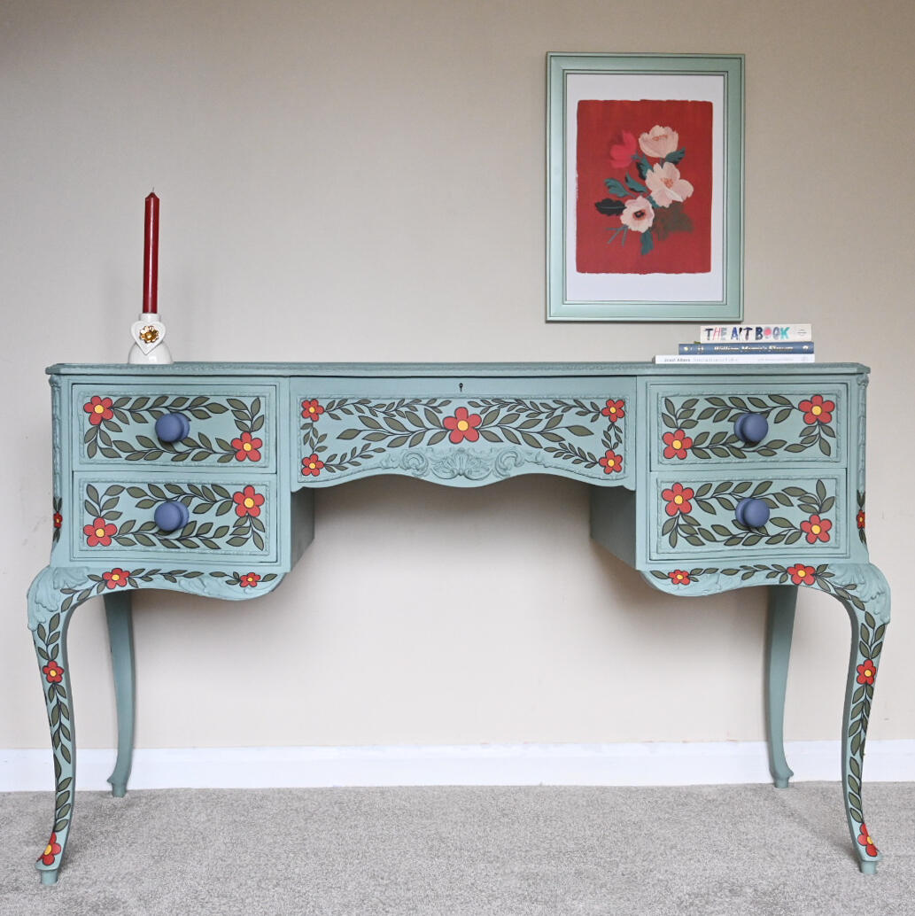 Duck egg blue dressing table with red and green floral hand painted design Duck egg blue dresser with two drawers, decorated with red flowers and green leaves, featuring dark knobs and curved legs